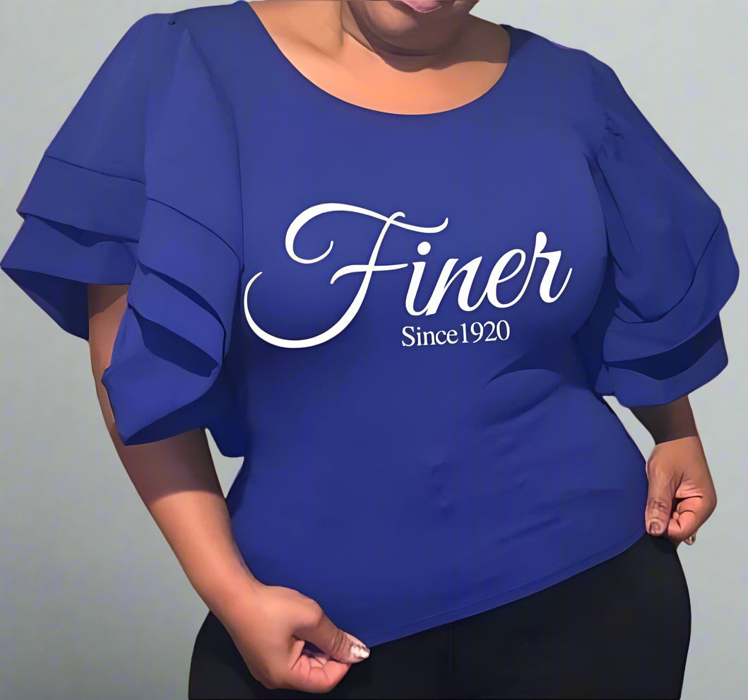 A woman wearing a royal blue blouse with ruffles, featuring the text 'Finer Since 1920' on the front.
