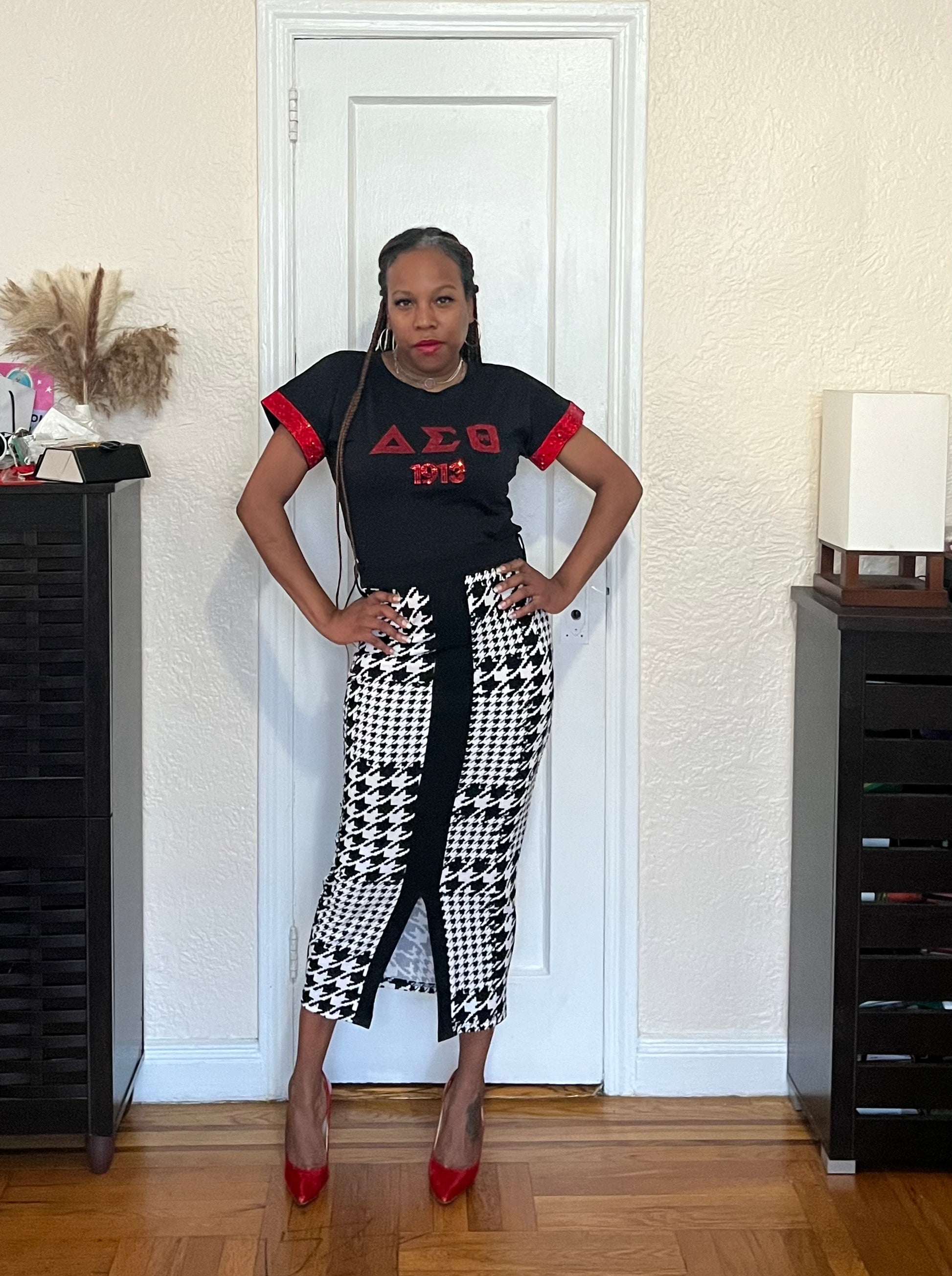 Turn heads in the All That Bling Shirt | Delta, featuring an original design made from a soft, super-stretch cotton spandex blend. The rhinestone-finished sleeves and bedazzled Delta Sigma Theta letters sparkle with Soror pride. Available in Black with Red rhinestones or Red with Black rhinestones.