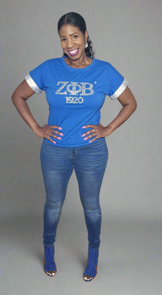 The All That Bling Shirt is a cotton-stretch tee that fits true to size for everyday comfort. It features a rhinestone front and blinged-out cuff sleeves for that perfect Zeta sparkle. Easy to care for just wash inside out and hang dry.