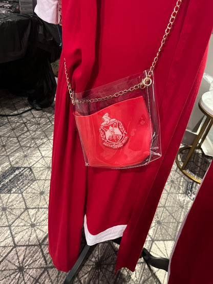 A red, transparent, square-shaped Delta Sigma Theta stadium bag with a gold-colored chain strap,