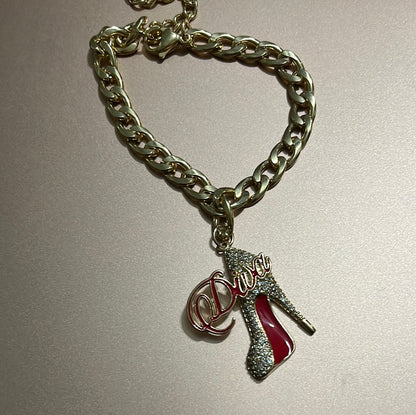 Add a touch of glam to your wrist with the Gold Diva Shoe Bracelet, featuring a chic gold heel charm with a signature red bottom. Stylish, feminine, and perfect for everyday wear or special occasions, this piece gives your look the perfect pop of diva energy.