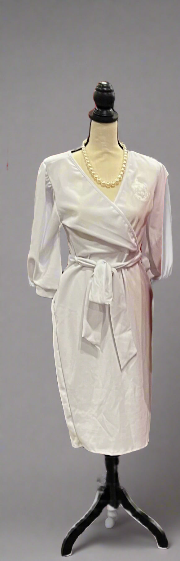 Step into elegance with The Chloe Delta Version. This all-white faux wrap dress features convenient pockets and the Delta Sigma Theta crest on the chest. Designed for a flattering fit that blends sophistication and Soror pride perfect for conferences, meetings, or special events.